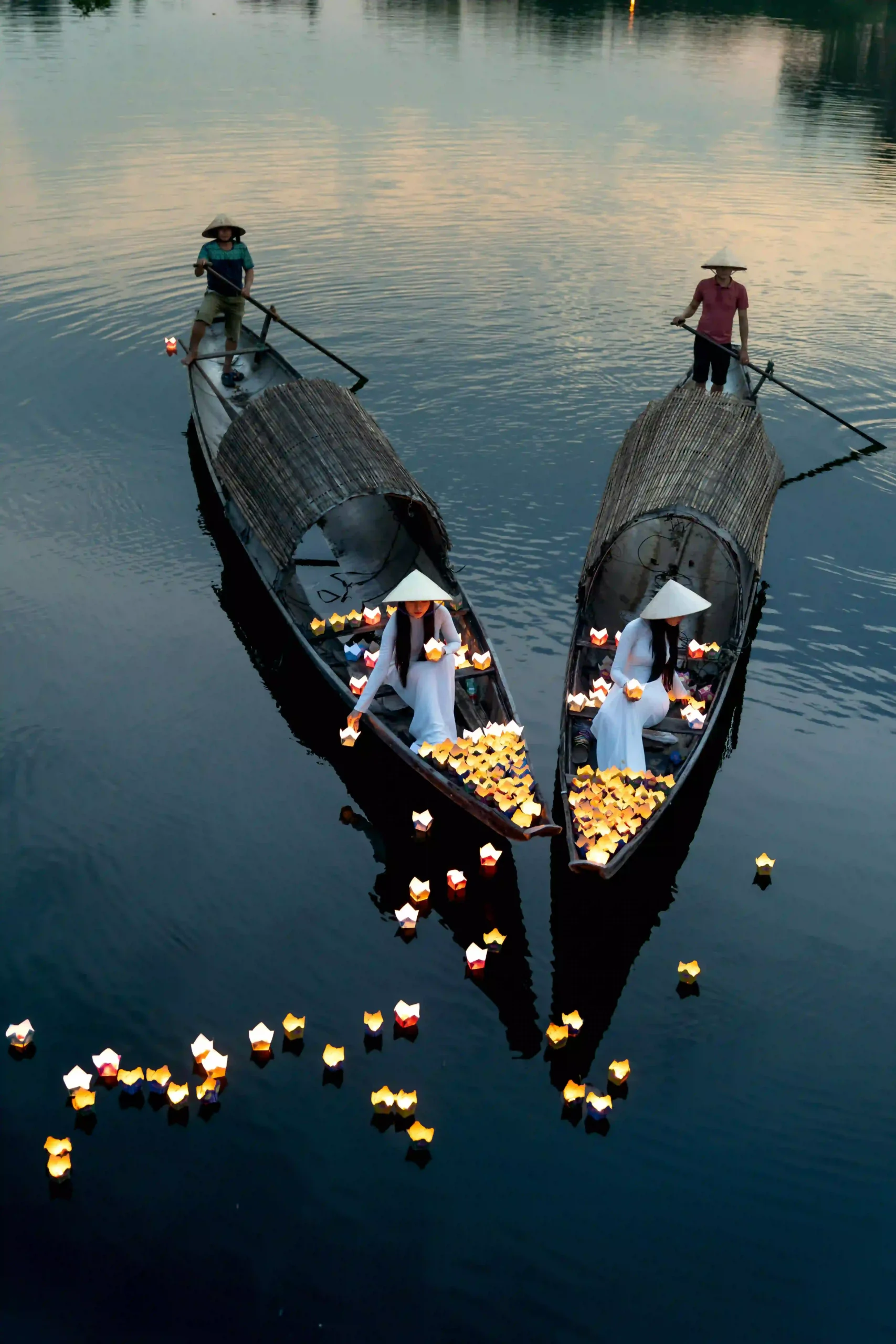 A person releasing a vibrant, glowing lantern onto a river in Hoi An, Vietnam at night