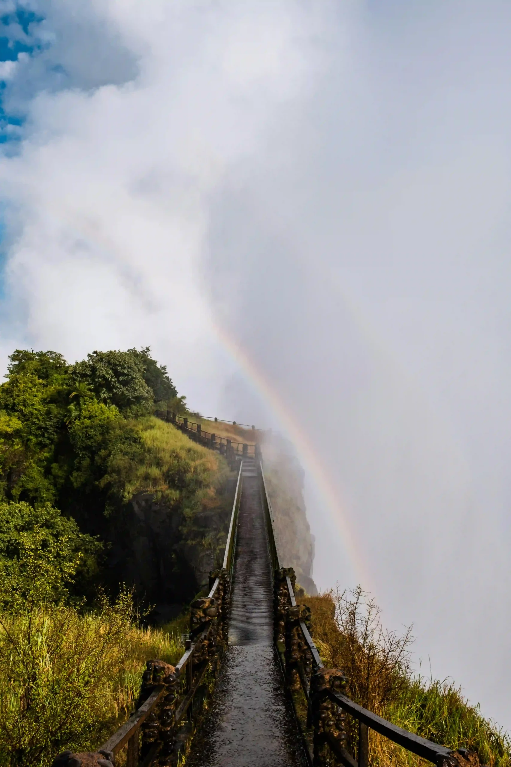 A rainbow over the misty bridge at the base of Victoria Falls.