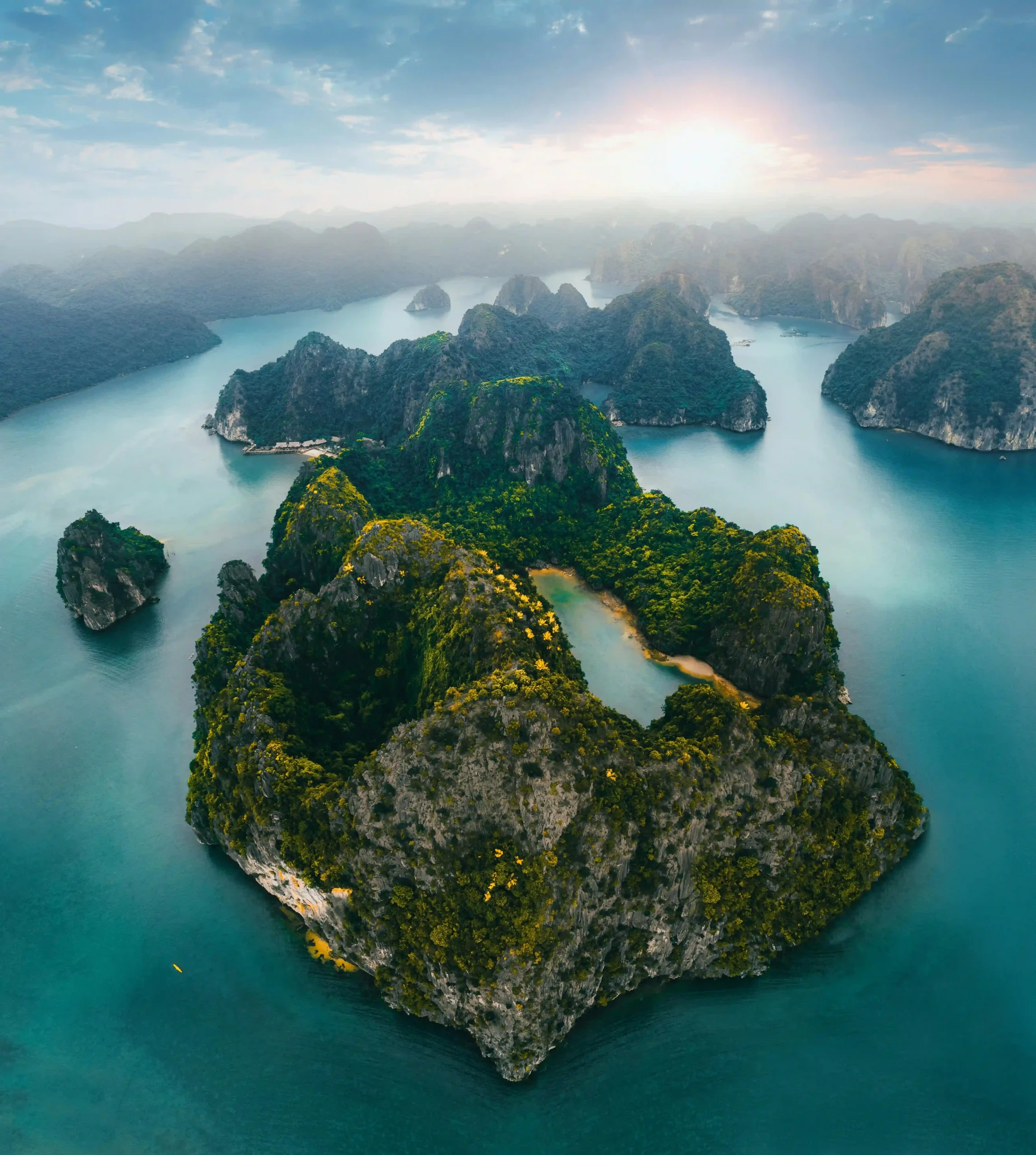 Aerial sunset view of boats in the emerald waters of Ha Long Bay, Vietnam.